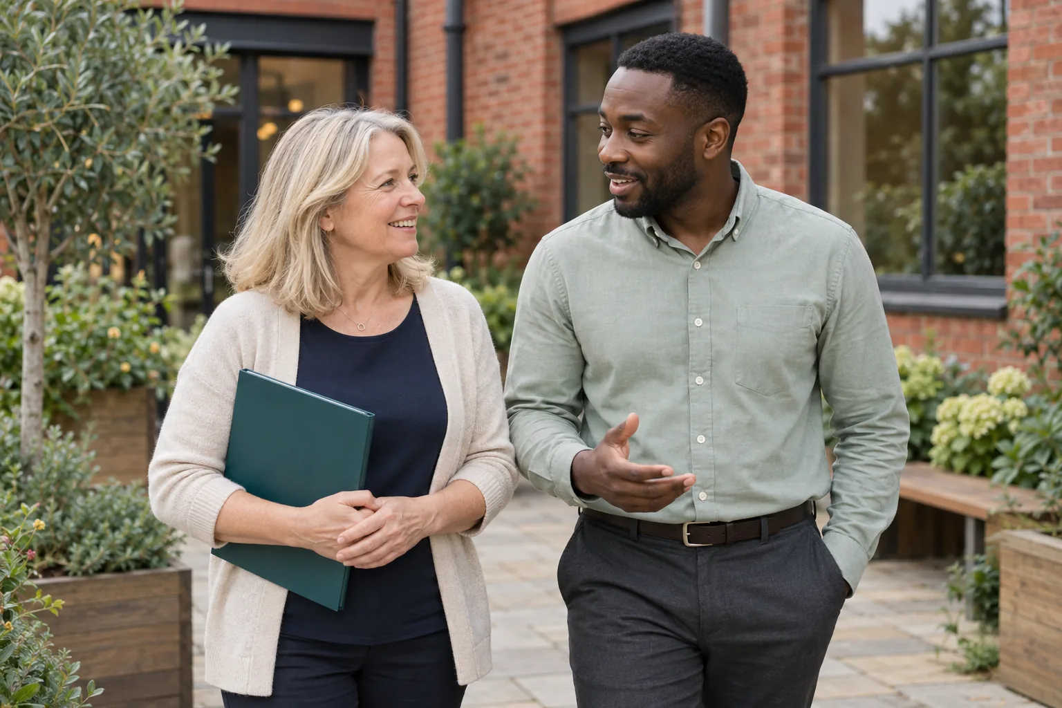 Two professionals having a friendly conversation in an office courtyard.